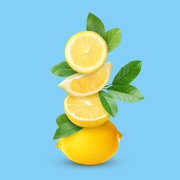 Stacked cut and whole lemons with green leaves on light blue background