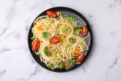 Plate of delicious pasta primavera on white marble table, top view