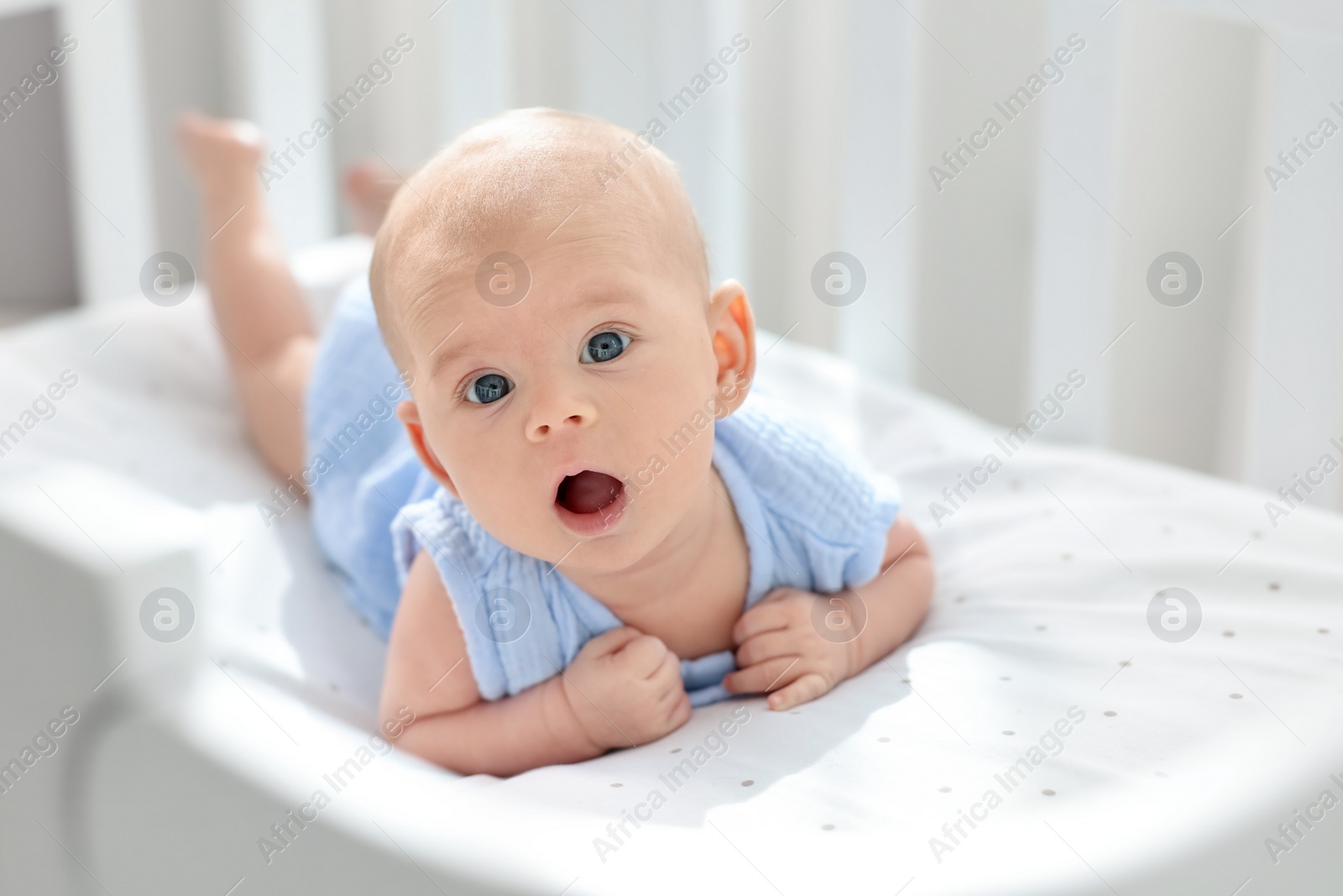 Photo of Cute little baby lying in crib at home, space for text