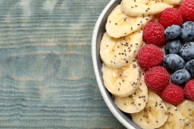 Photo of Tasty breakfast dish with berries, banana and chia seeds on wooden table, top view. Space for text