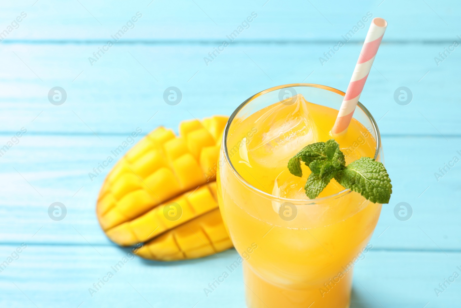 Photo of Fresh mango drink and cut fruit on blue wooden table, closeup. Space for text