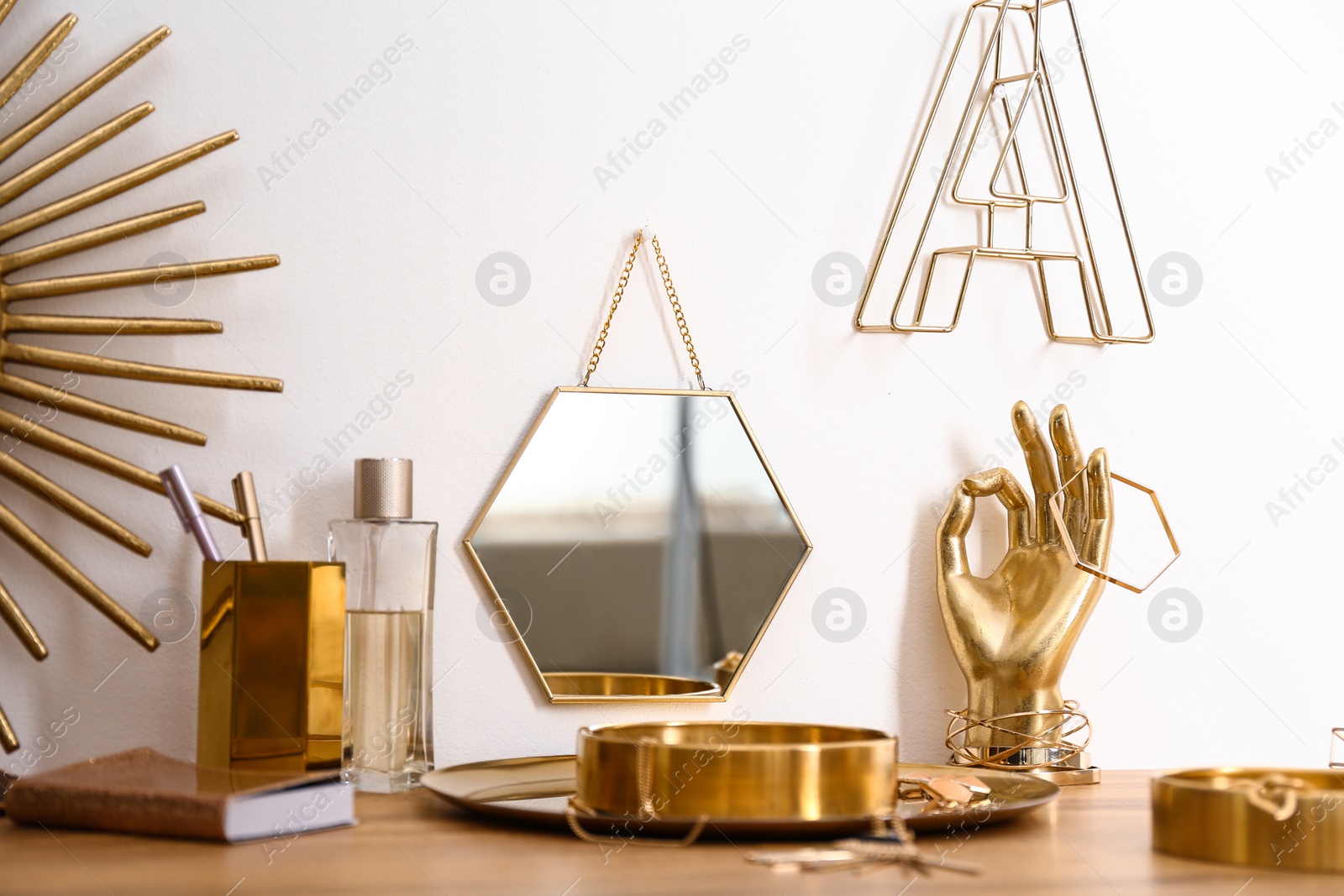 Photo of Composition with gold accessories on dressing table near white wall