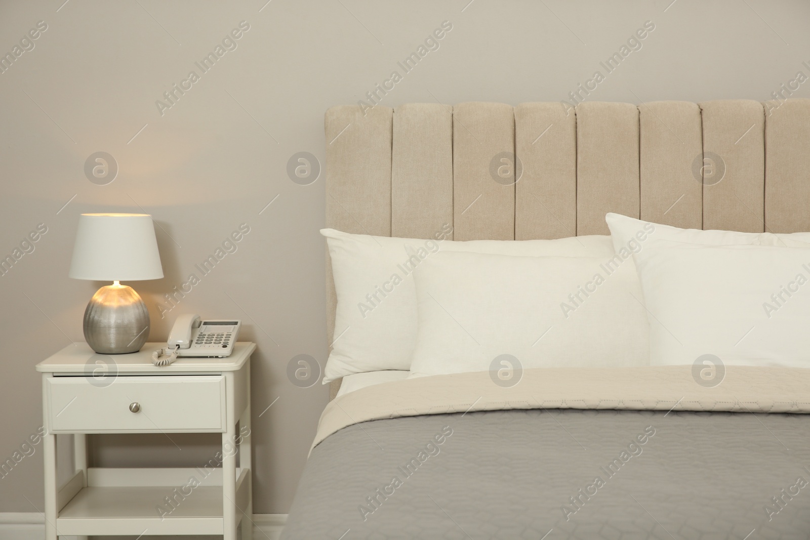 Photo of Comfortable bed and lamp on nightstand in hotel room