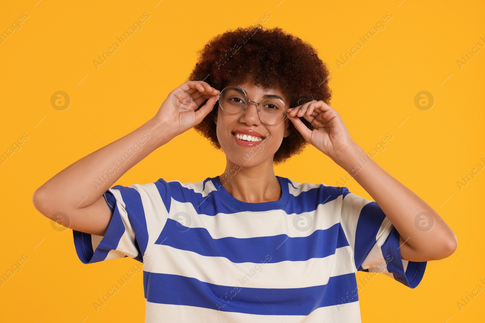 Photo of Portrait of happy young woman in eyeglasses on orange background