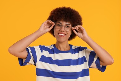 Photo of Portrait of happy young woman in eyeglasses on orange background