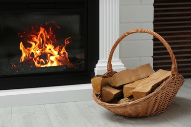 Firewood in wicker basket near fireplace indoors