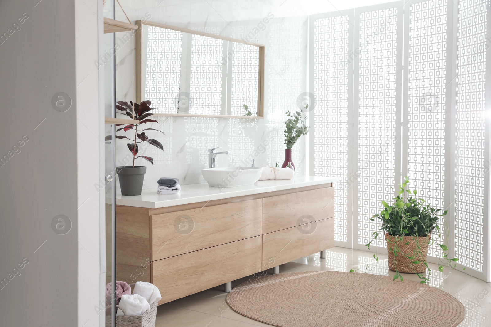 Photo of Stylish bathroom interior with countertop, mirror and plants. Design idea