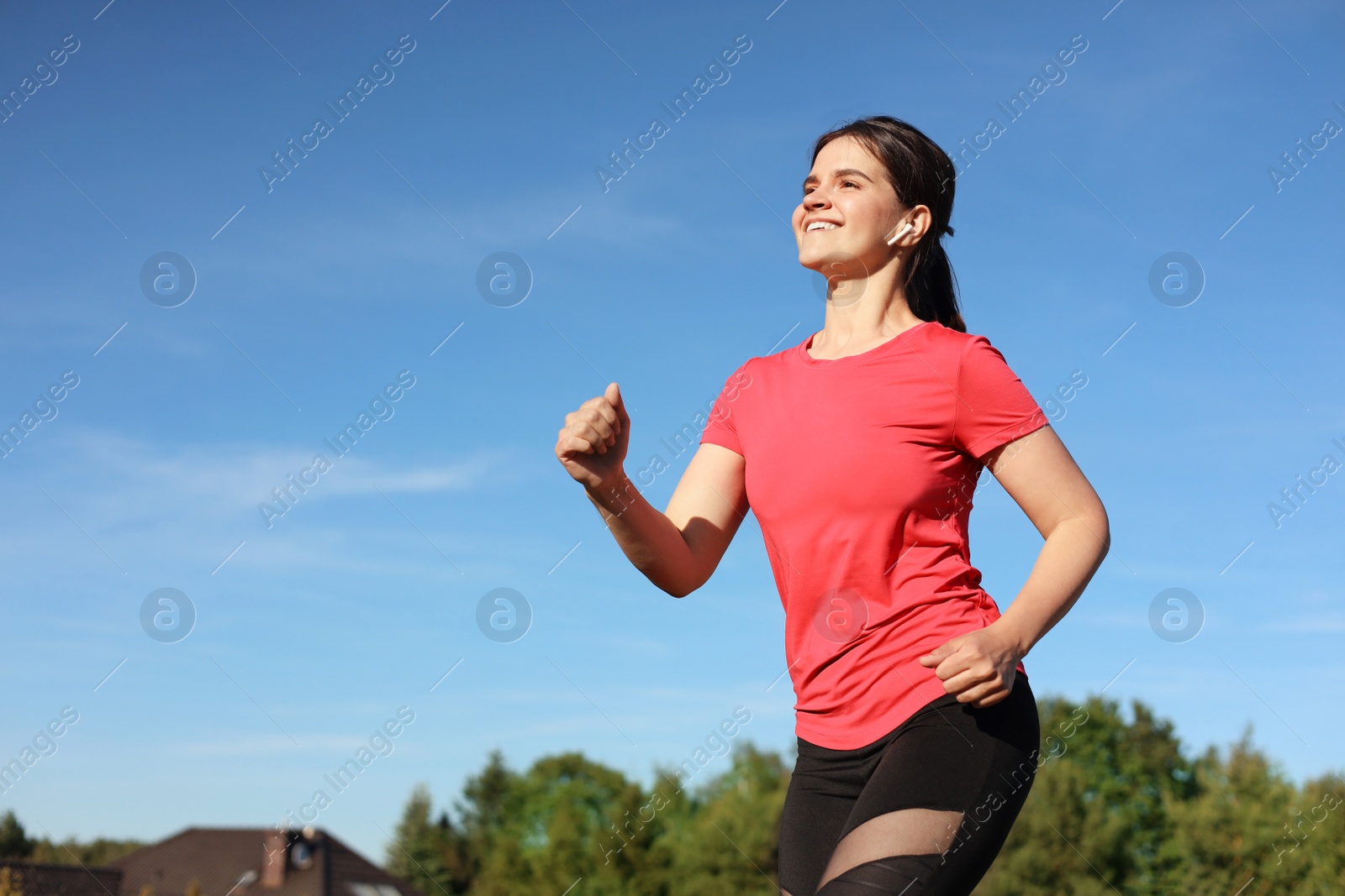 Photo of Young woman listening to music while running outdoors in morning. Space for text