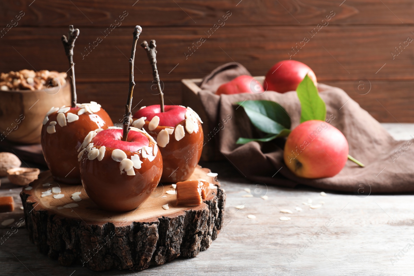 Photo of Delicious caramel apples on wooden serving board