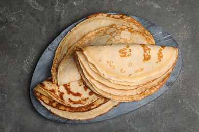 Photo of Fresh thin pancakes on grey table, top view