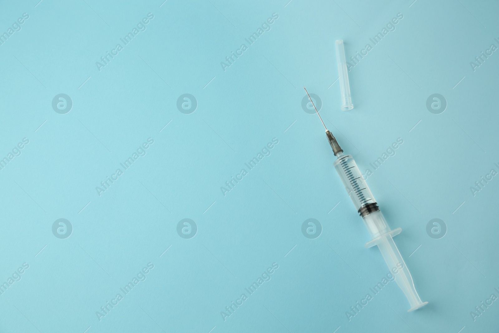 Photo of Medical syringe on light blue background, top view. Space for text