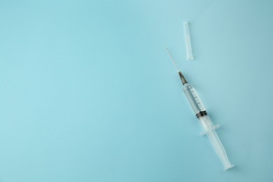 Medical syringe on light blue background, top view. Space for text