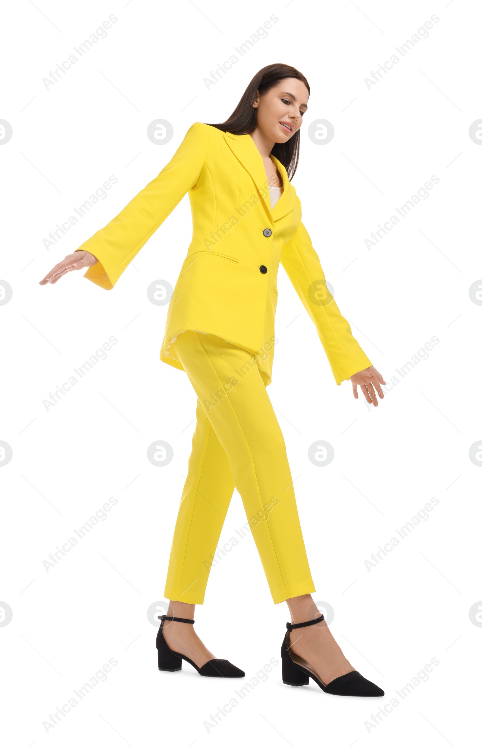 Photo of Beautiful businesswoman in yellow suit walking on white background, low angle view