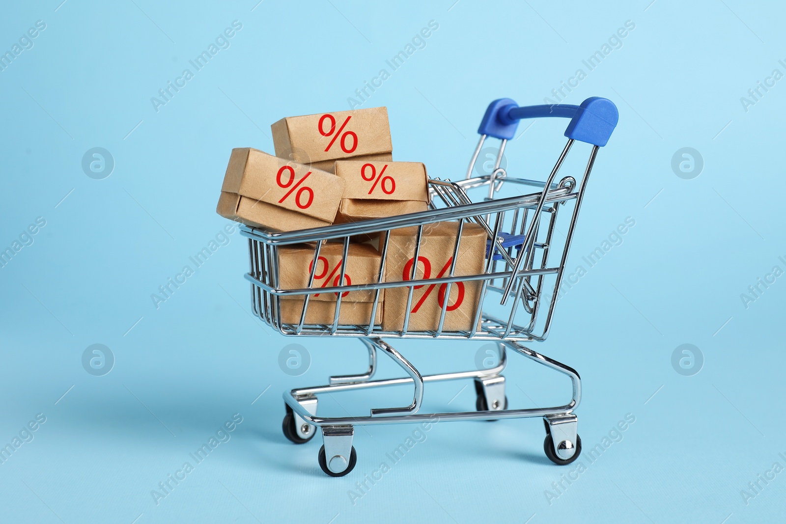 Image of Discount offer. Boxes with percent signs in mini shopping cart on light blue background