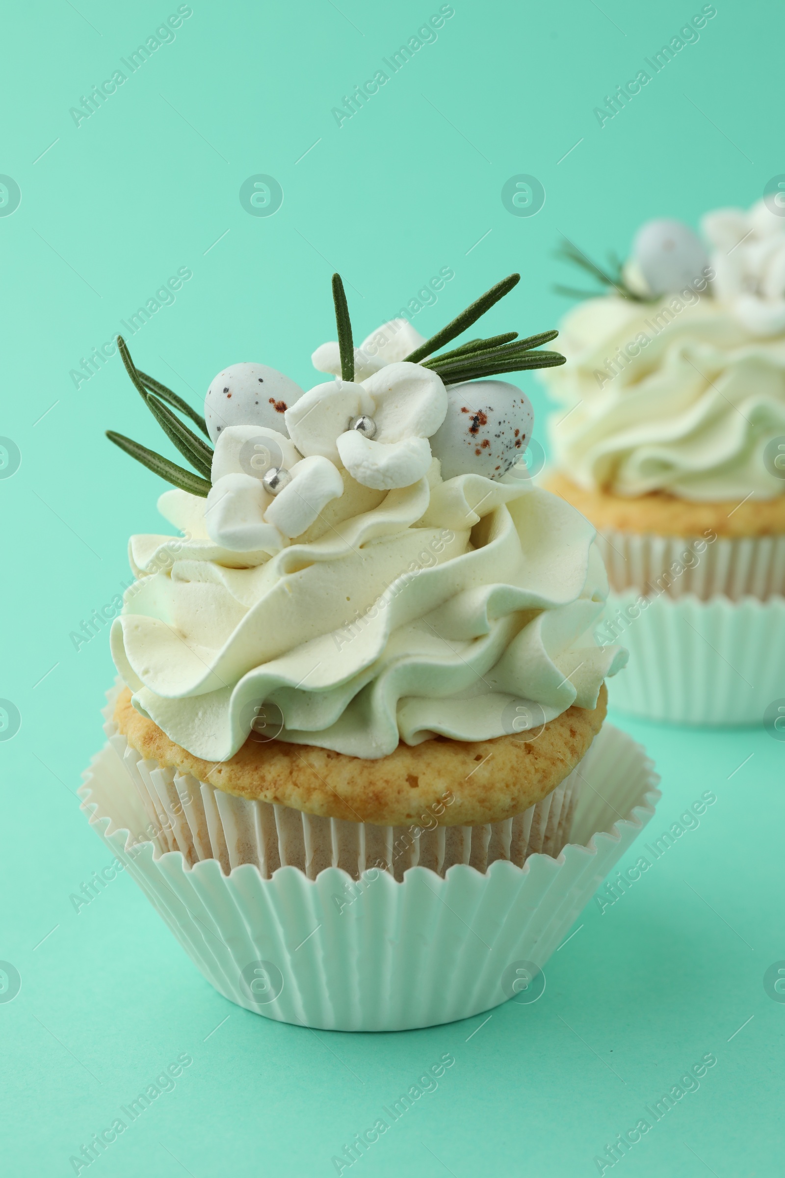 Photo of Tasty Easter cupcakes with vanilla cream on turquoise background