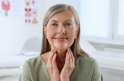 Photo of Endocrine system. Senior woman doing thyroid self examination indoors