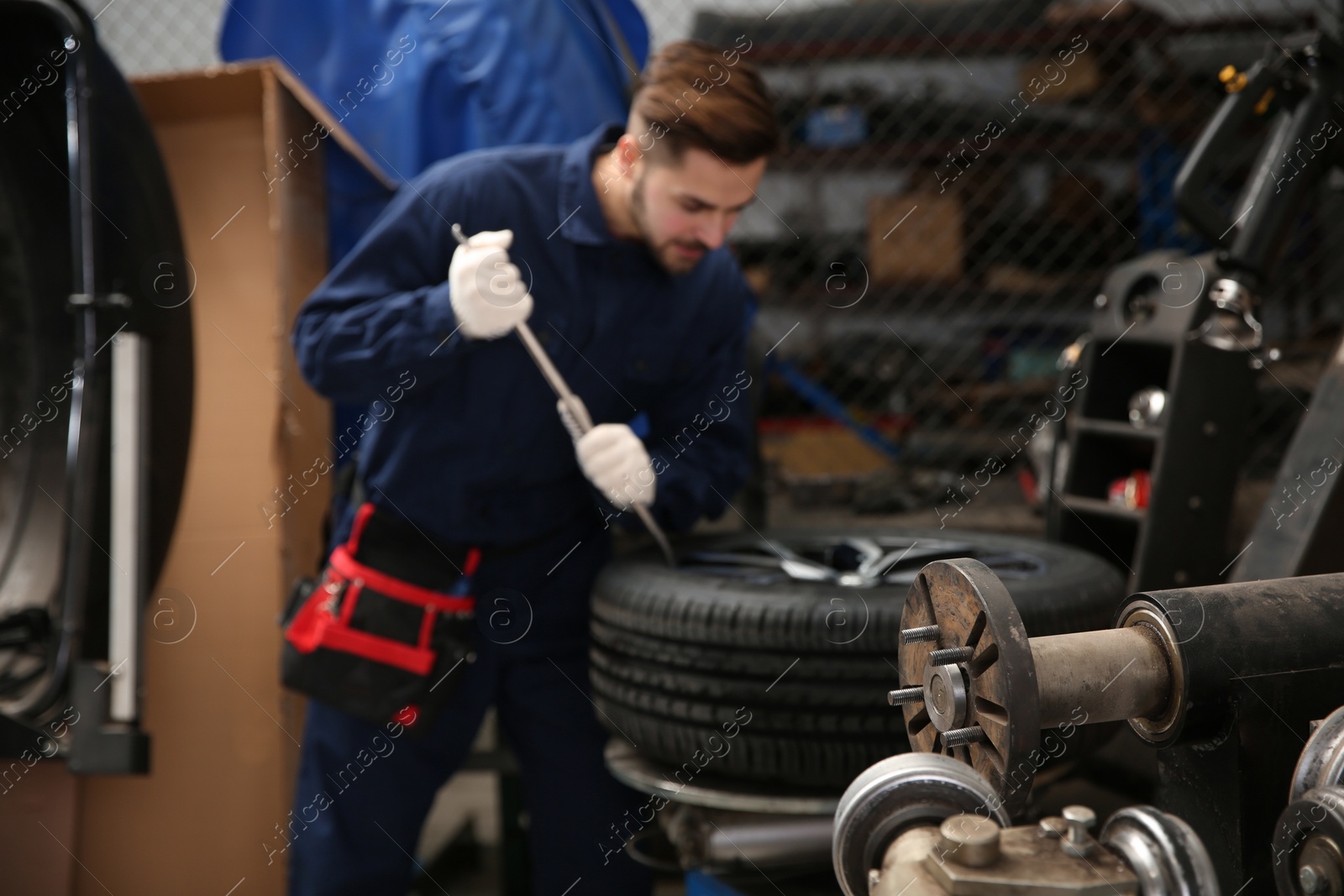 Photo of Technician working with car wheel at automobile repair shop