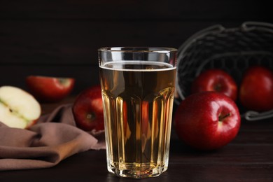 Photo of Glass of delicious cider and ripe red apples on wooden table