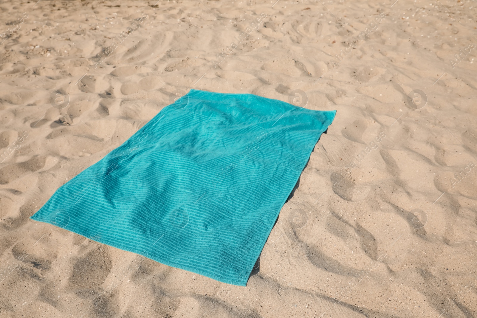 Photo of Turquoise soft beach towel on sunlit sand
