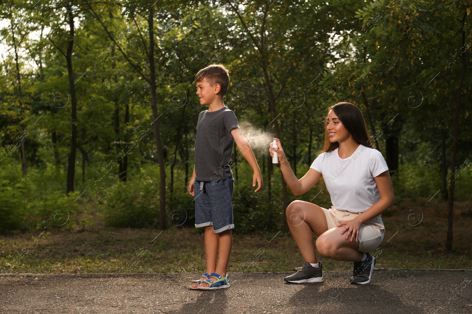 Photo of Woman applying insect repellent on her son's arm in park. Tick bites prevention