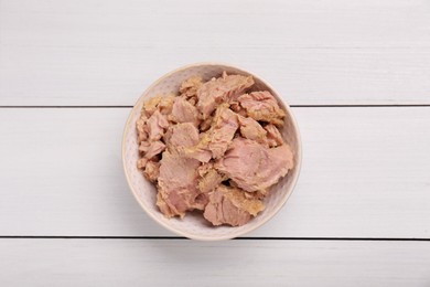 Photo of Bowl with canned tuna on white wooden table, top view