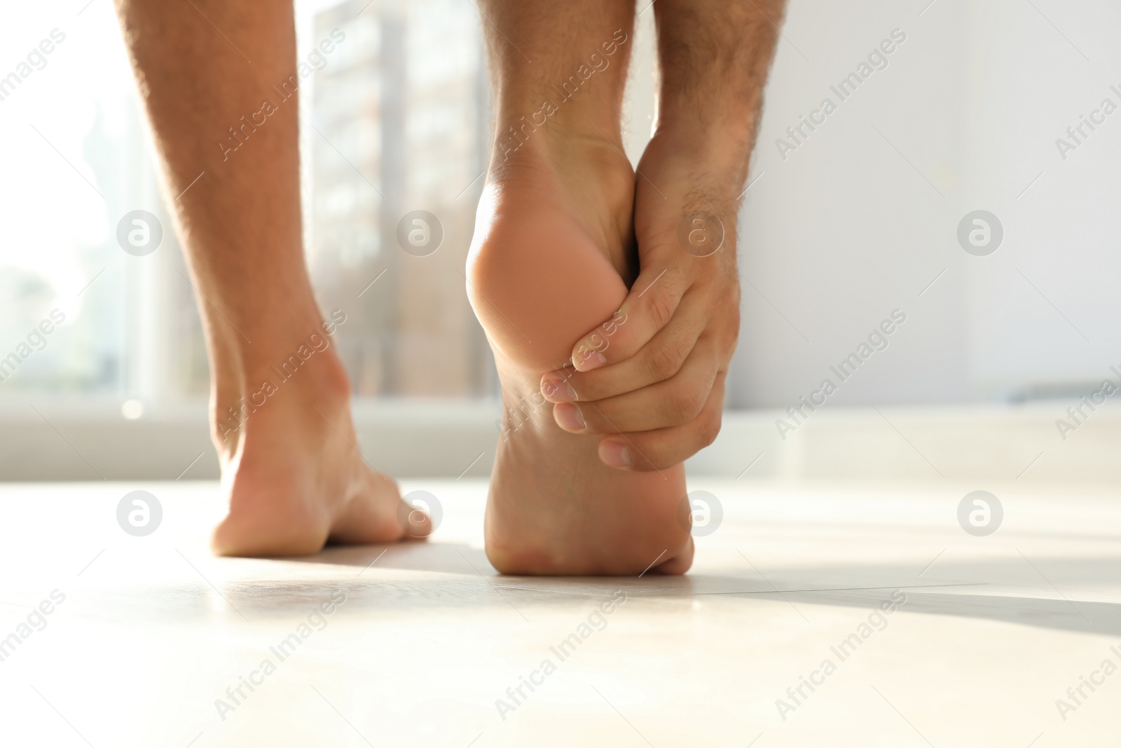 Photo of Back view of man suffering from foot pain indoors, closeup. Space for text