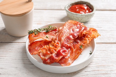 Plate with fried bacon on table