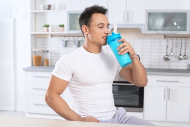 Young man drinking protein shake in kitchen