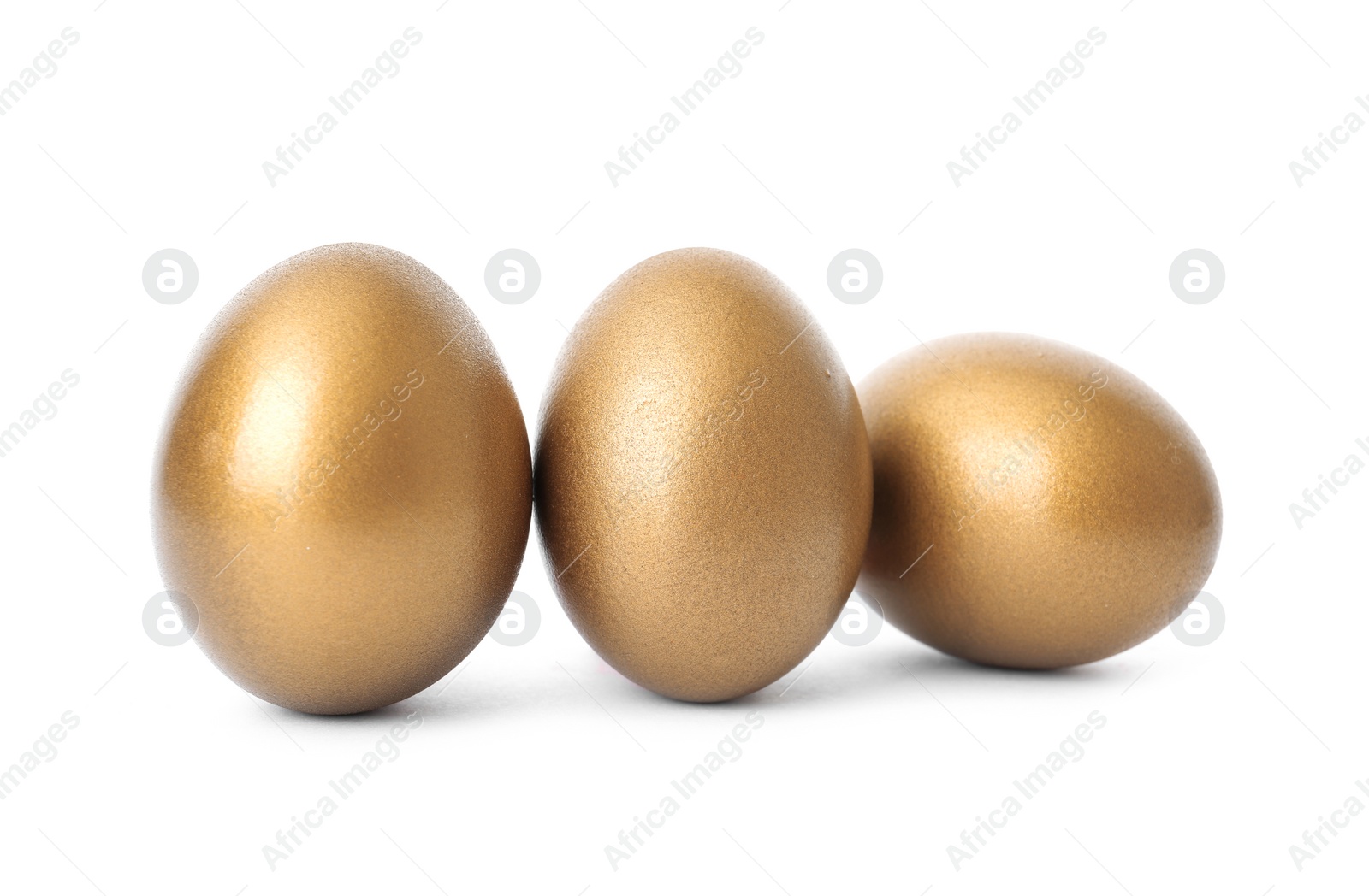 Photo of Three shiny golden eggs on white background