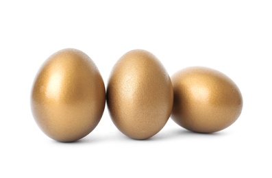 Photo of Three shiny golden eggs on white background