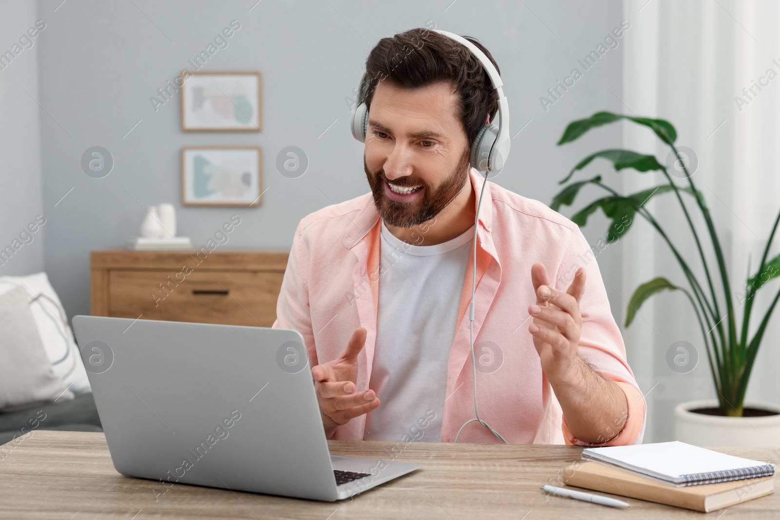 Photo of Man in headphones having video chat via laptop at home