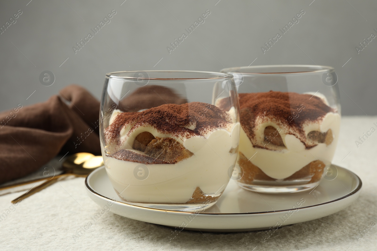 Photo of Delicious tiramisu in glasses on white table