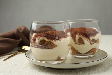 Photo of Delicious tiramisu in glasses on white table