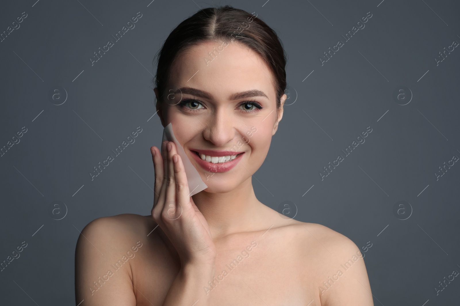 Photo of Beautiful woman using mattifying wipe on grey background