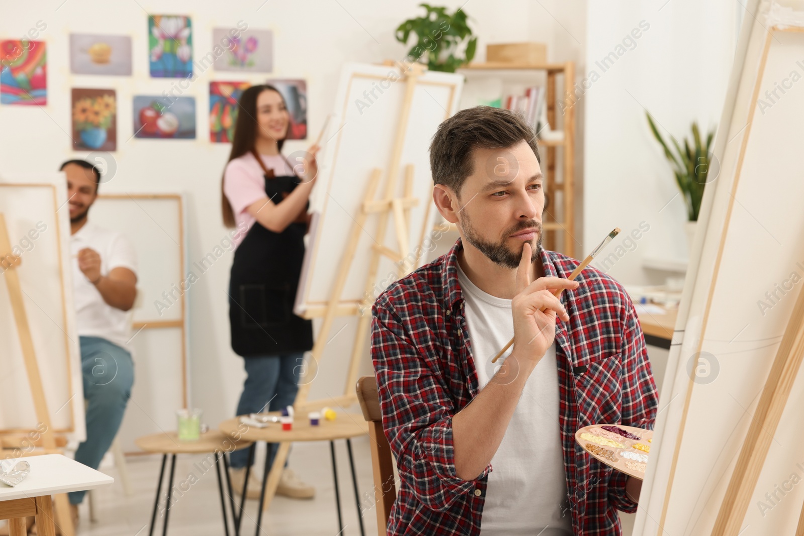 Photo of Group of students attending painting class in studio. Creative hobby