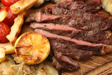 Photo of Delicious grilled beef with vegetables and lemon on table, closeup