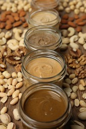 Nut butters in bowls and ingredients on wooden table, closeup