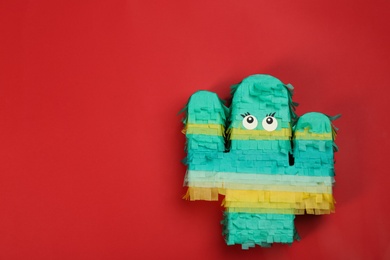 Photo of Bright cactus pinata on red background, top view. Space for text
