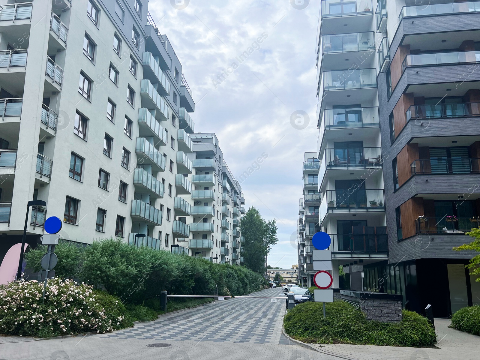 Photo of City street with buildings green plants unfer cloudy sky, low angle view