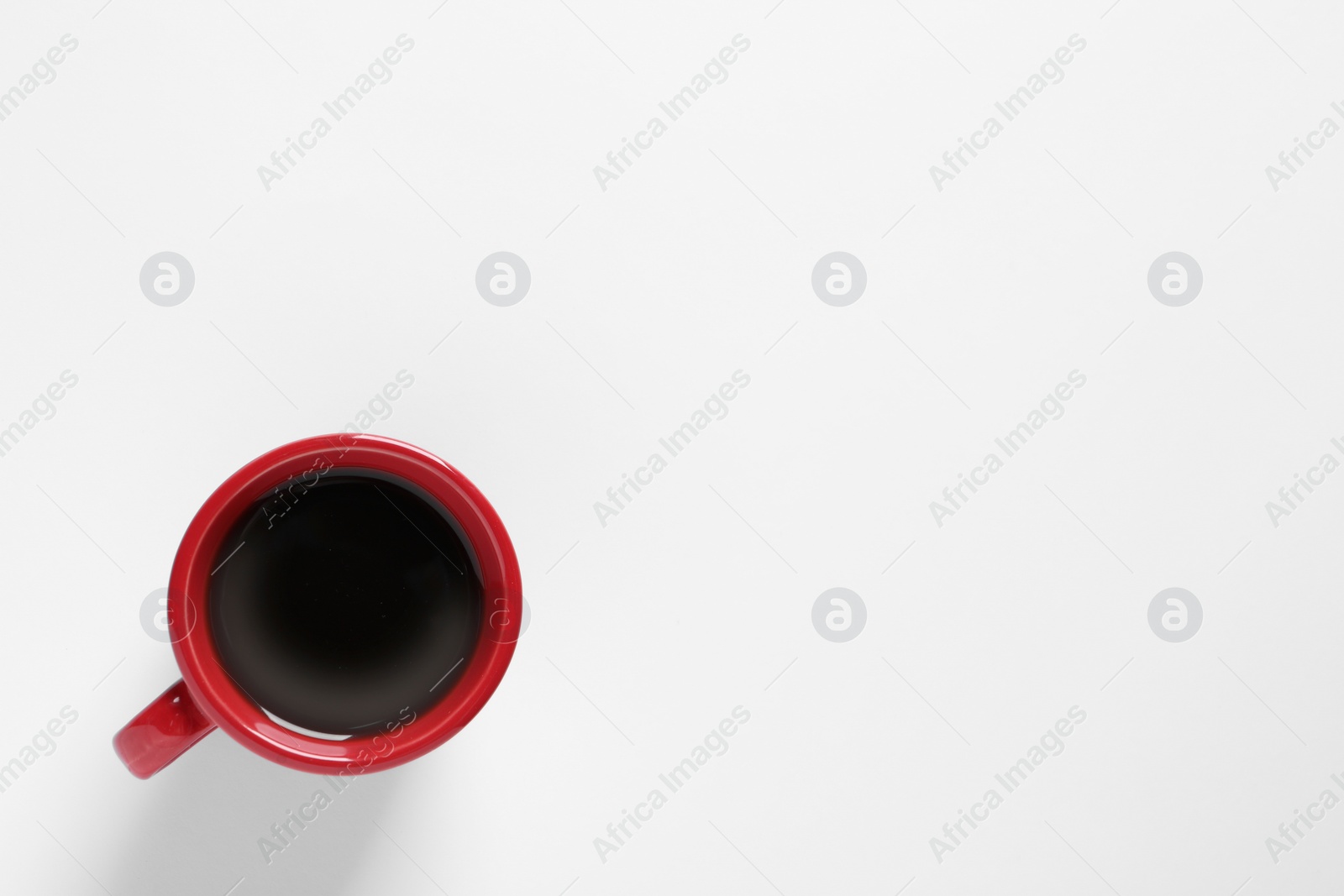 Photo of Red cup with aromatic coffee on white background, top view. Space for text