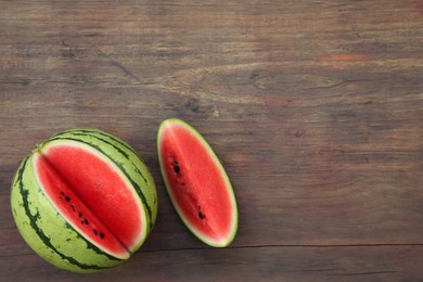 Photo of Cut delicious ripe watermelon on wooden table, top view. Space for text