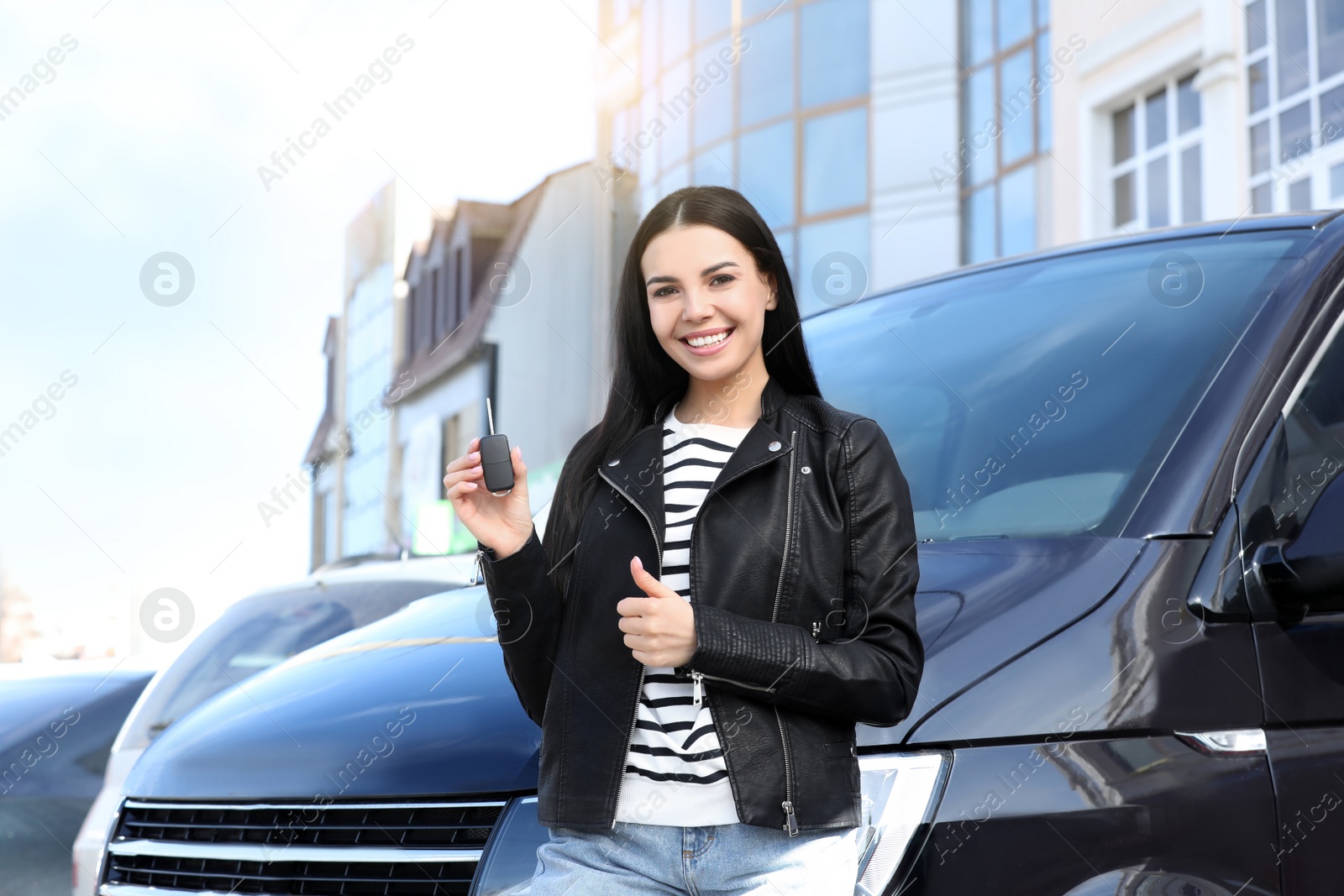 Photo of Young woman with key near car on city street. Buying new auto