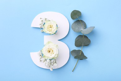 Photo of Paper number 3, beautiful flowers and eucalyptus branch on light blue background, top view