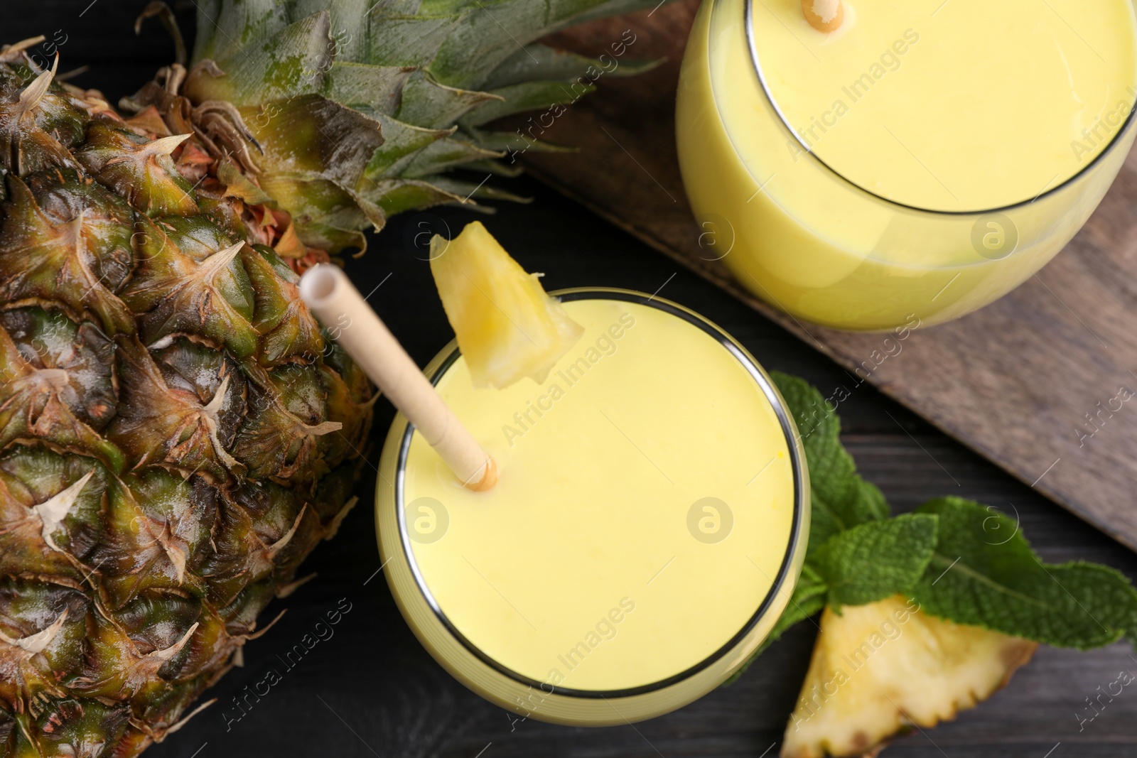 Photo of Tasty pineapple smoothie, mint and fruit on table, flat lay