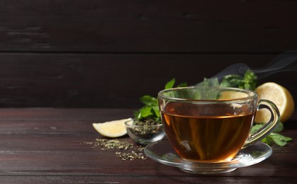 Glass cup of freshly brewed tea on wooden table. Space for text