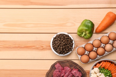 Photo of Flat lay composition with dry and natural dog food on wooden background. Space for text