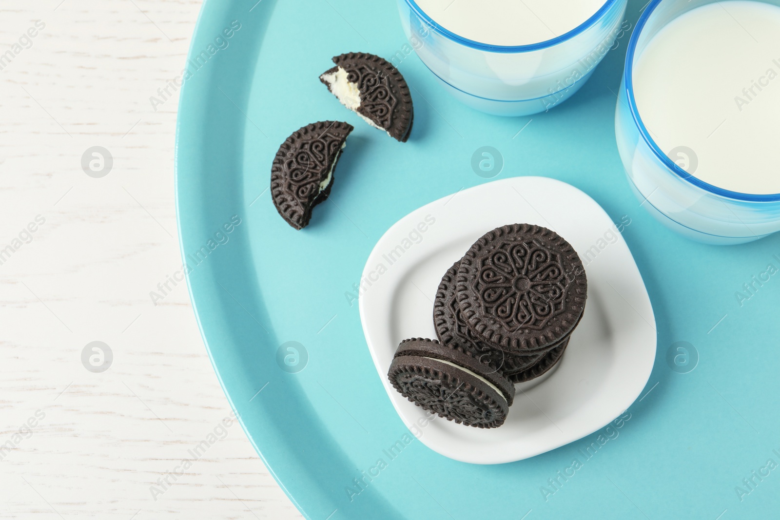 Photo of Tray with tasty chocolate cookies and glasses of milk on wooden background, top view