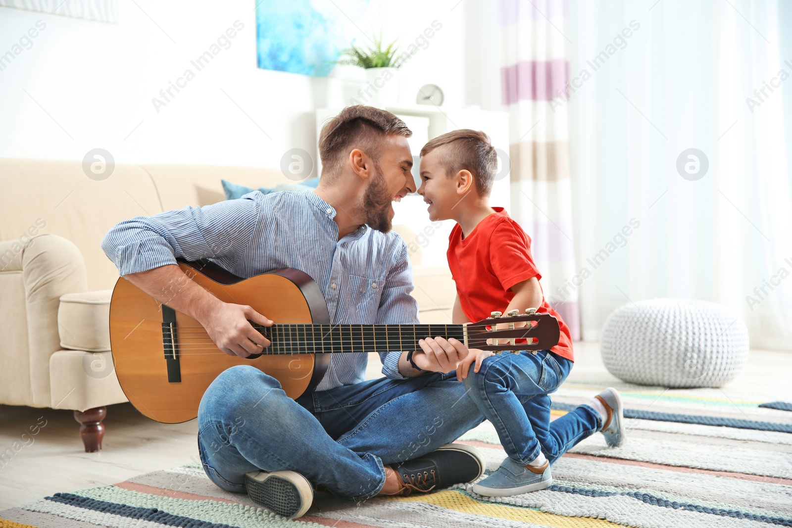 Photo of Father playing guitar for his son at home