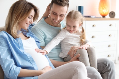 Photo of Young pregnant woman with her family at home