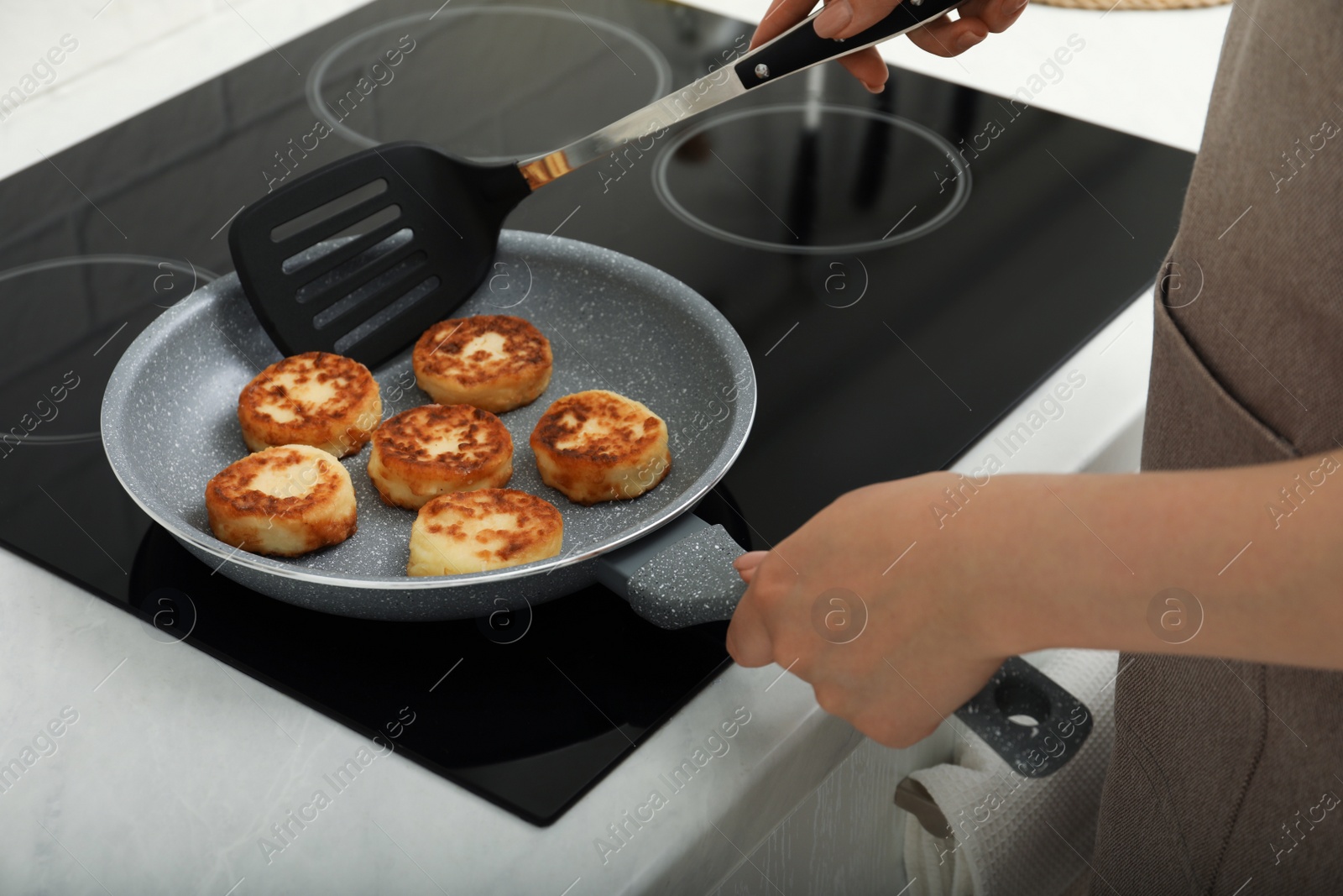Photo of Woman frying delicious cottage cheese pancakes in kitchen, closeup
